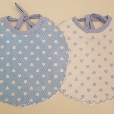 Dois babetes redondos de tecido com corações e laços para amarrar