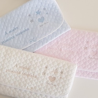 Três fraldas acolchoadas em branco, azul e rosa com bordados e texto
