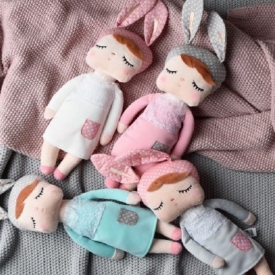 Bonecas de tecido com roupas coloridas e orelhas de coelho sobre mantas de malha