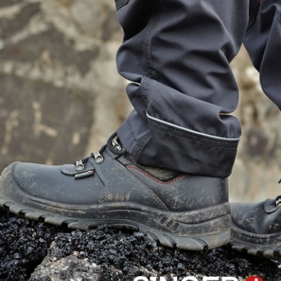 Botas de segurança pretas com solado robusto em superfície de pedra, com logo SINGER safety
