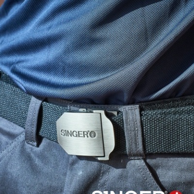 Cinto preto com fivela metálica SINGER em calças escuras e t-shirt azul