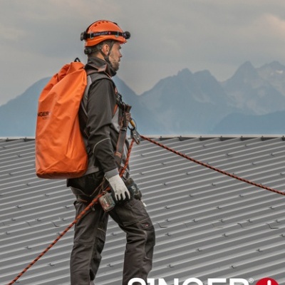 Trabalhador com equipamento de segurança num telhado metálico cinzento