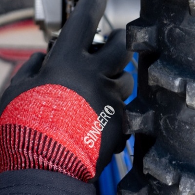 Mão com luva preta e vermelha a mexer numa corrente de bicicleta perto de pneu