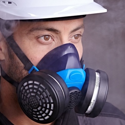 Homem com capacete branco e máscara respiratória azul com filtros pretos