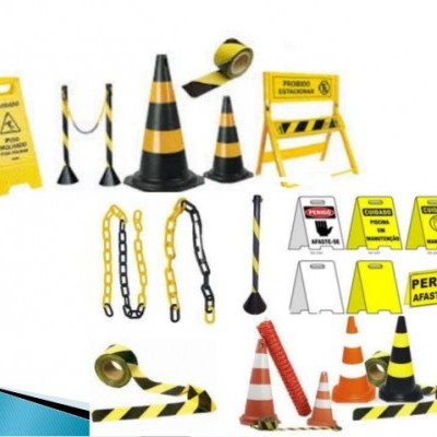 Acessórios de sinalização de segurança amarelos e pretos com cones, fitas e placas de aviso.
