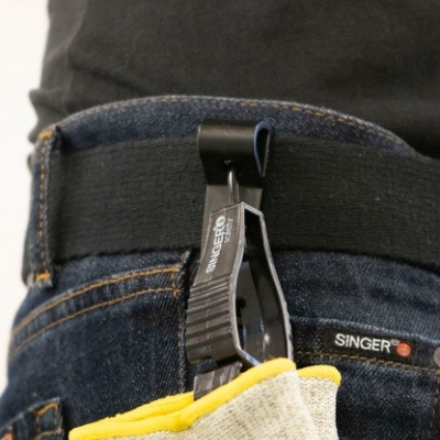 Prendedor de pano preto com marca Magneto pendurado em cinto sobre jeans azuis