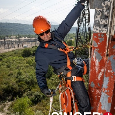 Trabalhador em equipamento de proteção pendurado em estrutura metálica com logo SINGER safety
