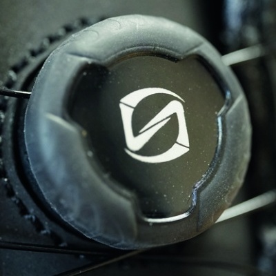 Roda dentada preta com logotipo branco central sobre fundo preto