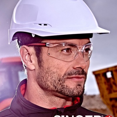 Homem com capacete branco, óculos de segurança, vestuário escuro; texto SINGER safety