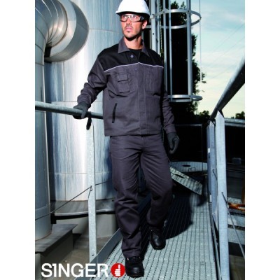 Homem com uniforme de trabalho cinza escuro e preto, capacete branco e luvas pretas numa passarela industrial