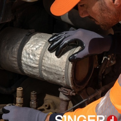 Homem com luvas de segurança cinza SINGER a mexer numa peça metálica com isolamento térmico.