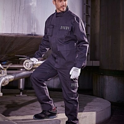 Homem com macacão cinzento escuro, capacete branco e luvas brancas em ambiente industrial, texto SINGER safety