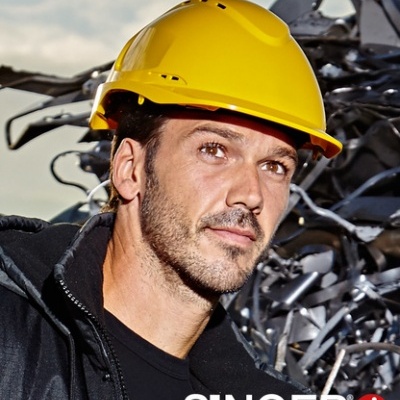 Homem com capacete amarelo de segurança e roupa preta junto a sucata metálica com logo SINGER safety