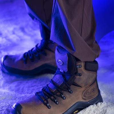 Bota de trekking marrom com atacadores pretos e sola preta sobre chão de neve sob luz azul