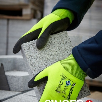 Luvas de segurança amarelas com preto segurando bloco de cimento cinza