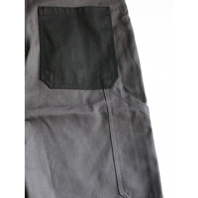 Peça de vestuário cinzenta com bolso preto quadrado e costuras visíveis