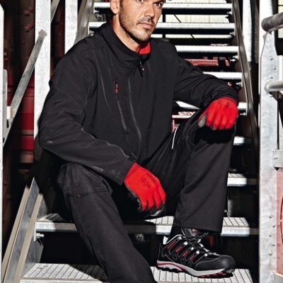 Homem com roupa de trabalho preta, luvas vermelhas, boné e sapatos em escada metálica