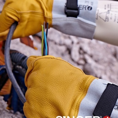 Luvas de proteção amarelas e cinzentas segurando cabos elétricos