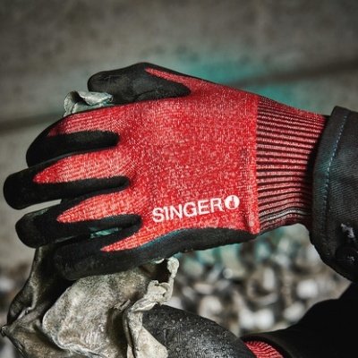 Luvas vermelhas e pretas com texto SINGER a segurar objeto cinzento