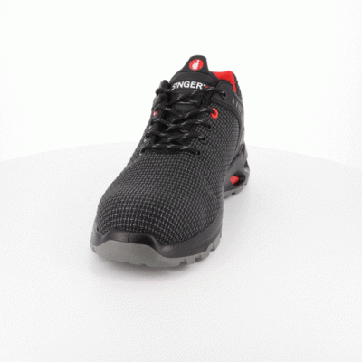 Ténis desportivo preto com detalhes vermelhos sobre superfície branca