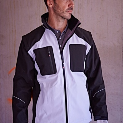 Homem com casaco de segurança preto e branco, boné e luvas brancas, em fundo de parede de cimento cinza