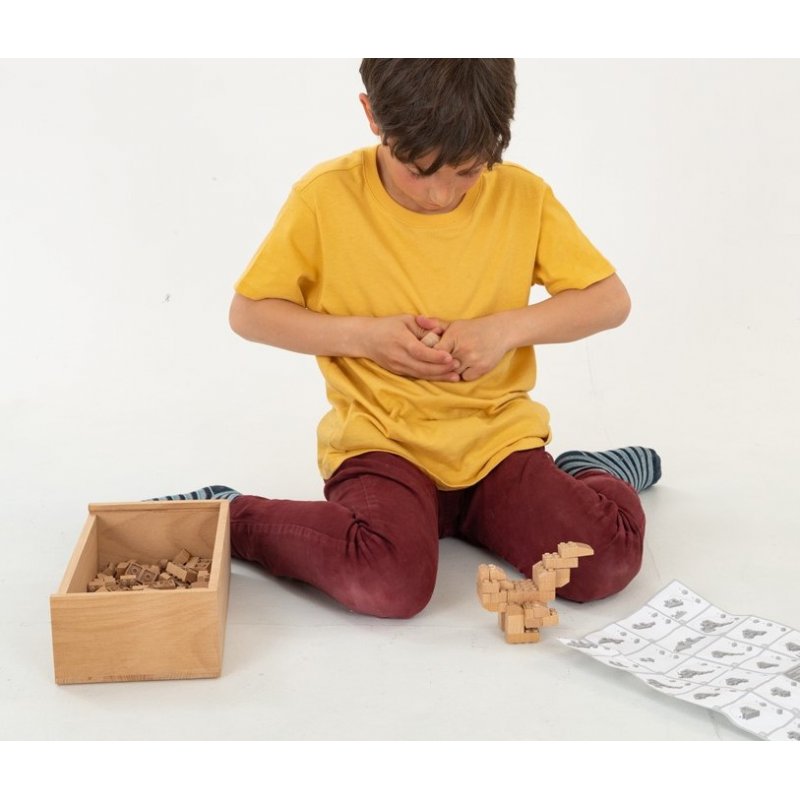 Fab Brix 150 Peças - Master Box Menino brincando com blocos de madeira e folha de instruções sentado no chão branco