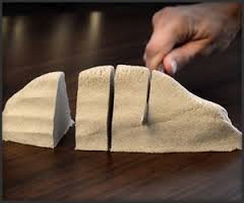 Areia Cinética (5kg) Queijo amarelo claro cortado em fatias sobre superfície de madeira com mão segurando