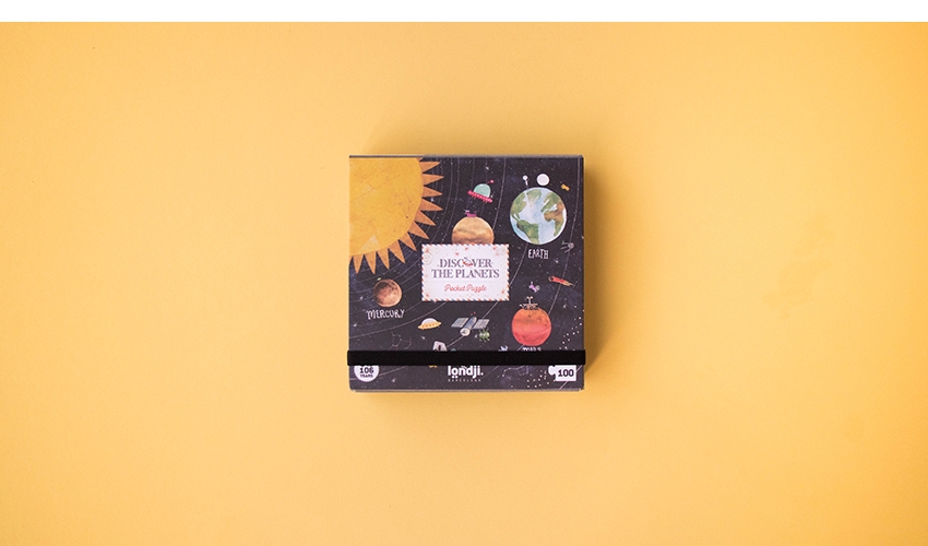 Puzzle Pocket Descobre o Planeta Caixa de jogo ou quebra-cabeça sobre superfície amarela com imagens do sistema solar.