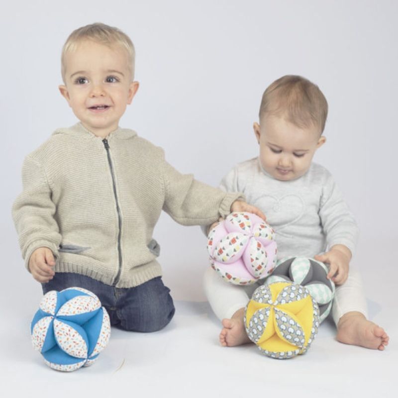Duas crianças sentadas segurando bolas de tecido coloridas com padrões diversos