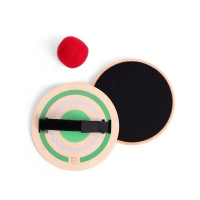 Brinquedo com mira circular verde e preta, base preta e bola vermelha em fundo branco