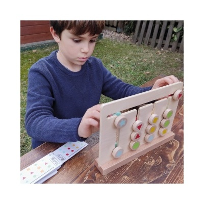 Menino a usar brinquedo educativo de madeira com peças coloridas