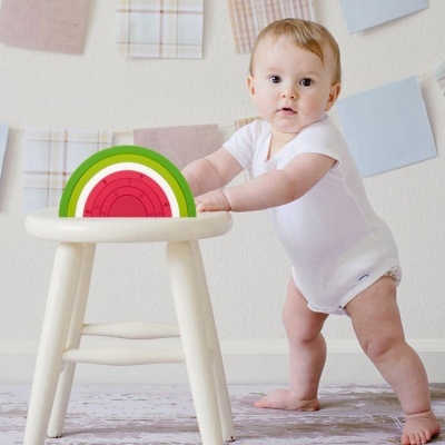 Bebé com brinquedo de madeira colorido sobre cadeira branca