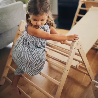Escada triangular de madeira para crianças com tecido bege e criança a brincar