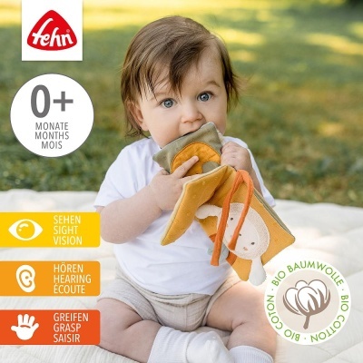 Bebé a brincar com brinquedo macio em tecido colorido sentada ao ar livre