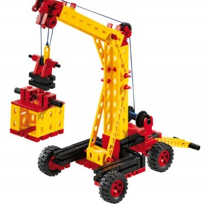 Brinquedo de grua com peças amarelas, vermelhas e pretas, caixa amarela pendurada e rodas vermelhas em fundo branco