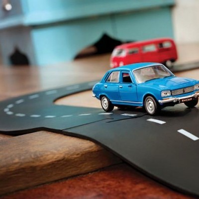 Miniaturas de carros de brinquedo numa pista de corrida sobre chão de madeira