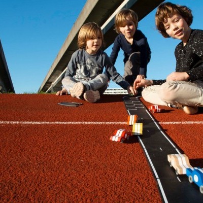Crianças a jogar com carros de madeira numa pista desportiva
