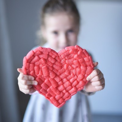 Menina segurando coração rosa de espuma