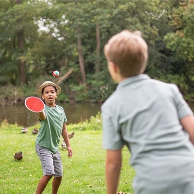 Crianças a jogar ténis de mesa ao ar livre num parque verde