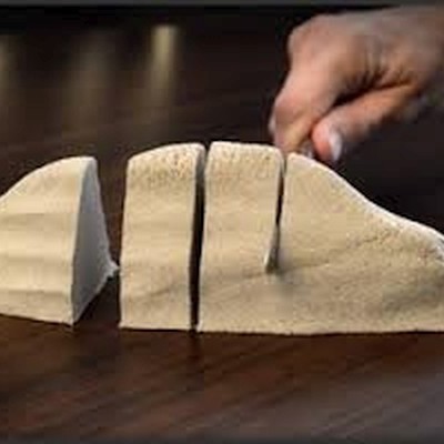 Queijo amarelo claro cortado em fatias sobre superfície de madeira com mão segurando