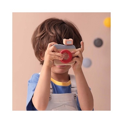 Criança a segurar câmara fotográfica de brinquedo em madeira