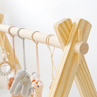 Estrutura de madeira com brinquedos pendurados de crochê em tons neutros