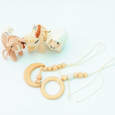 Bonecos de croché de animais e brinquedos de madeira com cordas num fundo branco