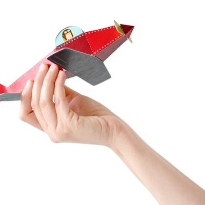 Mão segurando avião vermelho de brinquedo de madeira