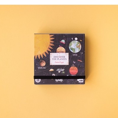 Caixa de jogo ou quebra-cabeça sobre superfície amarela com imagens do sistema solar.