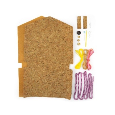 Materiais para artesanato com cortiça, botões, fios coloridos e alfinetes sobre fundo branco.