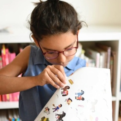 Criança com folha branca e imagens coloridas a olhar concentrada