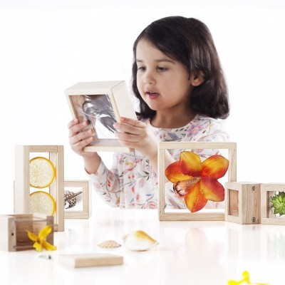 Criança a brincar com caixas de madeira transparentes com elementos naturais