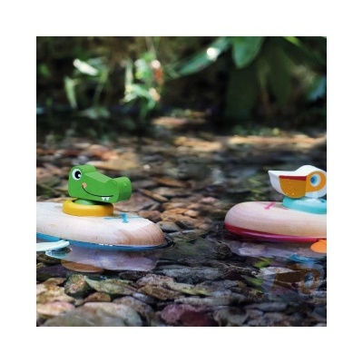 Brinquedos de madeira de crocodilo e pássaro a flutuar num riacho com pedras visíveis