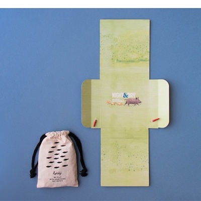 Embalagem verde aberta e saco tecido cor de rosa claro com cordão preto e texto preto num fundo azul